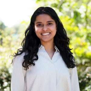 Ruchika's headshot, a brown-skinned woman with wavy black hair and a white top